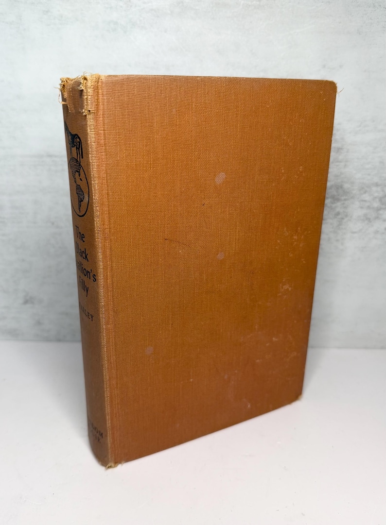 May include: A vintage hardcover book with a tan cover. The book's spine features the title "The Black Nation's Tilly" and a small illustration. The cover shows some wear and tear, with visible spots and discoloration.