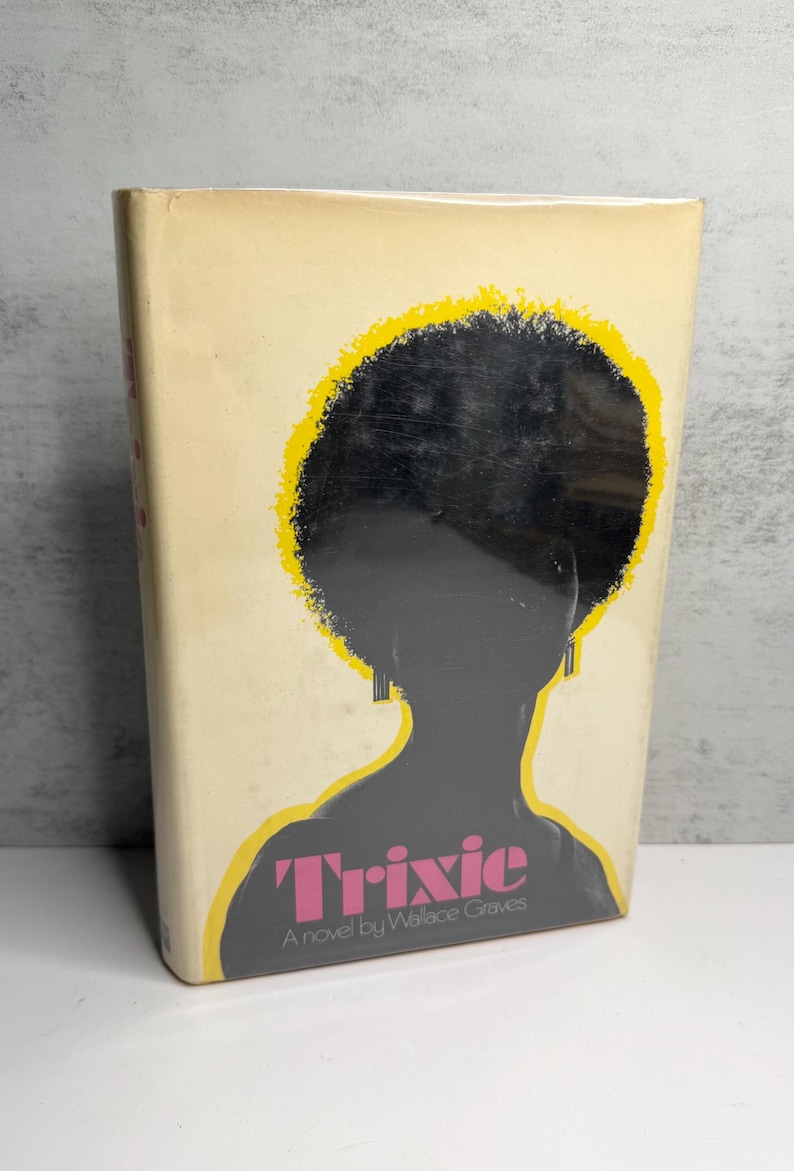 May include: Vintage paperback book titled "Trixie" by Wallace Graves. The cover features a silhouette of a person with an afro, outlined in yellow, with the title in pink. The book has a cream-coloured background.