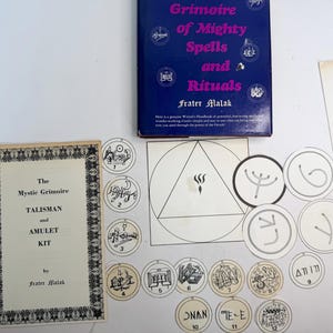 May include: A collection of mystical items including a book titled "Grimoire of Mighty Spells and Rituals" and a booklet labeled "The Mystic Grimoire Talisman and Amulet Kit." Also included are several circular tokens and a geometric diagram.