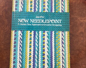May include: A book titled "Now Needlepoint" by Jan Orr. The cover features a colorful pattern of vertical stripes in shades of blue, yellow, and white. The book's subtitle reads "A Joyous New Approach to Creative Designing."