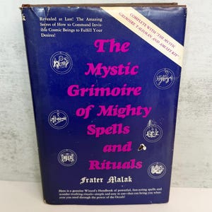 May include: A vintage book titled "The Mystic Grimoire of Mighty Spells and Rituals" with a blue cover and pink lettering. The book includes text about commanding cosmic beings and is part of a kit.