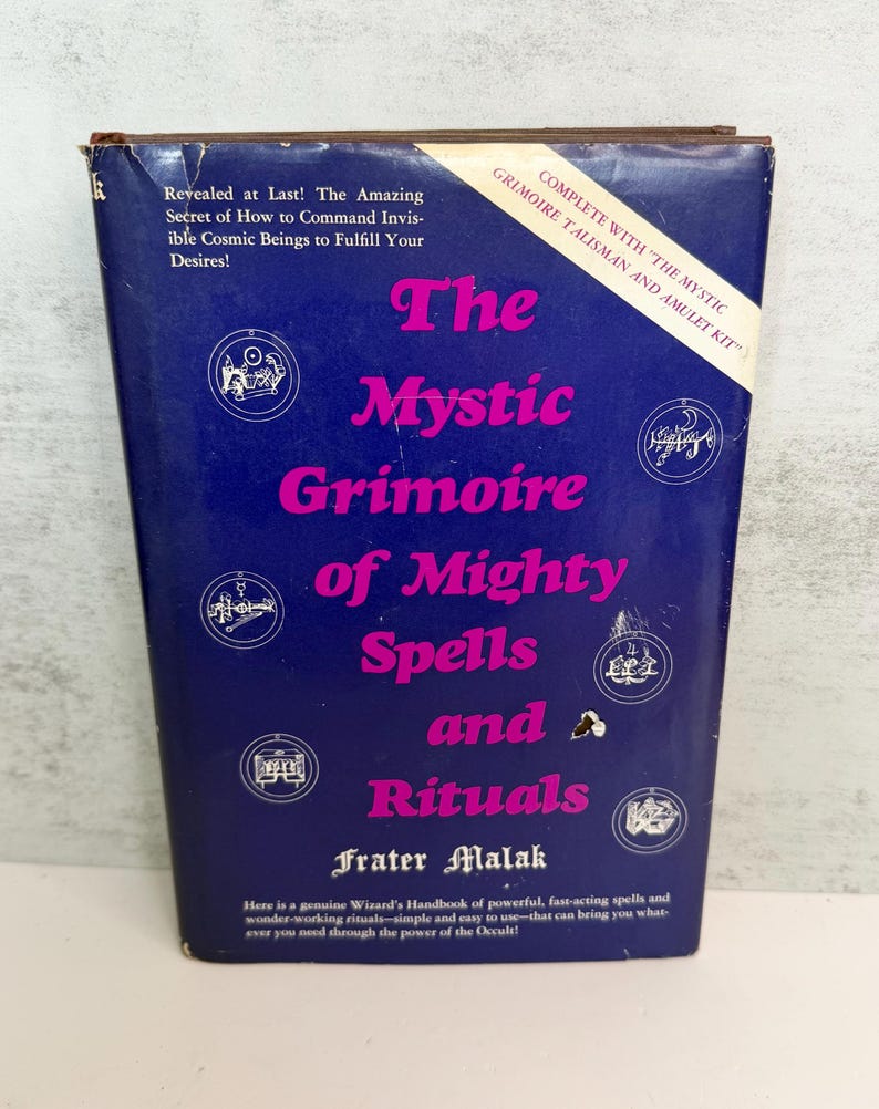 May include: A vintage book titled "The Mystic Grimoire of Mighty Spells and Rituals" with a blue cover and pink lettering. The book includes text about commanding cosmic beings and is part of a kit.