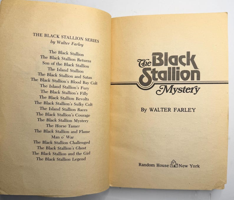 May include: Open book with the title "The Black Stallion Mystery" by Walter Farley. The book's cover features a stylized logo with the words "Black Stallion" in a decorative font. The left page lists other books in the series.