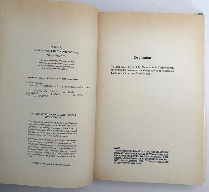 May include: Open book with text on aged paper. The left page includes publishing information, Library of Congress data, and the title "MYSTIC GRIMOIRE OF MIGHTY SPELLS AND RITUALS." The right page has a dedication. A note at the bottom warns against damaging the book.