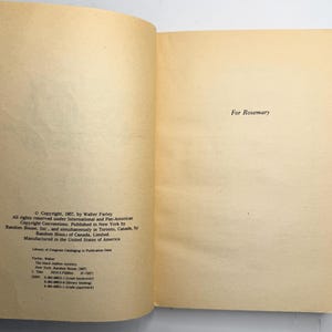 May include: Open book pages with text. The left page has copyright information, including the author's name and publisher. The right page reads "For Rosemary". The pages are aged with a yellowed tone.