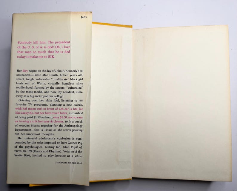 May include: An open book with aged pages and a yellow spine. The left page features text about Trixie Mae Smith. The right page is blank. The book's cover has a price tag of &pound;5.50, approximately.