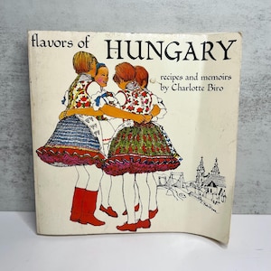 May include: A white ceramic mug with a black handle and the text "But First, Coffee" in a black, bold font. The mug is sitting on a wooden surface. The mug is approximately 4 inches tall.