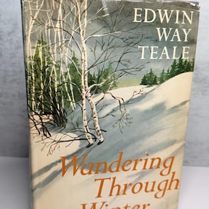 May include: A vintage book cover with a winter landscape illustration. The title "Wandering Through Winter" is in orange, with the author's name, Edwin Way Teale, above. The cover depicts a snowy scene with trees.