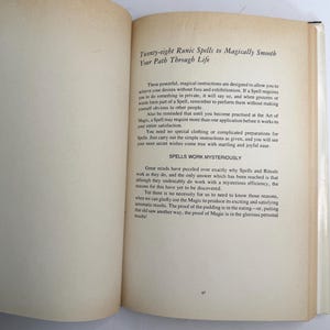 May include: An open book with text titled "Twenty-eight Runic Spells to Magically Smooth Your Path Through Life." The pages are off-white with black text. The book is open to a page with text about spells and rituals.