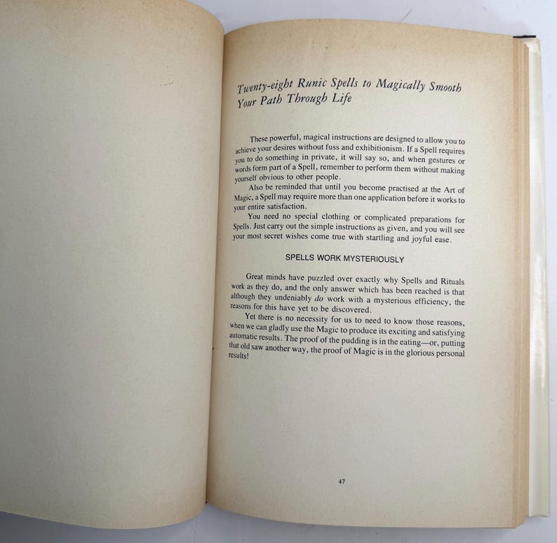 May include: An open book with text titled "Twenty-eight Runic Spells to Magically Smooth Your Path Through Life." The pages are off-white with black text. The book is open to a page with text about spells and rituals.