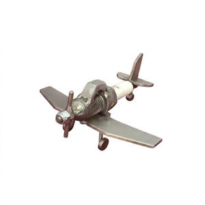 Op de afbeelding: Een handgemaakte metalen vliegtuigsculptuur met een propeller, vleugels en staart. De romp van het vliegtuig bevat een bougie. De sculptuur is zilverkleurig en staat op een witte achtergrond.