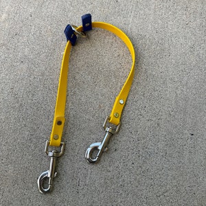 May include: A yellow dog leash with two silver clips and blue metal hardware.