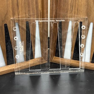 May include: A clear plastic template for making backgammon inlay. The template has five slots for inlay pieces and five rows of holes for screws. The text "Backgammon Inlay Template" is printed on the template.