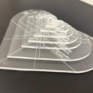 Może przedstawiać: Zestaw sześciu przezroczystych szablonów w kształcie serca z akrylu w różnych rozmiarach. Szablony są oznaczone tekstem "Pine Tree Crafts & Studio".