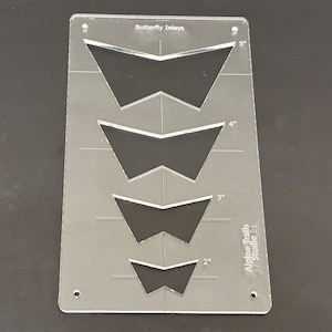 K&ouml;nnte beinhalten: Eine transparente Kunststoffschablone mit vier Schmetterlings-Einlegemustern. Die Schablone ist mit "Butterfly Inlays" beschriftet und enth&auml;lt Ma&szlig;e in Zoll: 2", 3", 4" und 5". Die Schablone wird von Alpine Trails Studio hergestellt.