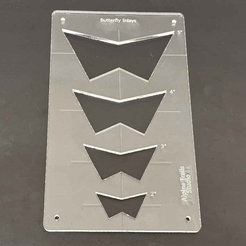 K&ouml;nnte beinhalten: Eine transparente Kunststoffschablone mit vier Schmetterlings-Einlegemustern. Die Schablone ist mit "Butterfly Inlays" beschriftet und enth&auml;lt Ma&szlig;e in Zoll: 2", 3", 4" und 5". Die Schablone wird von Alpine Trails Studio hergestellt.