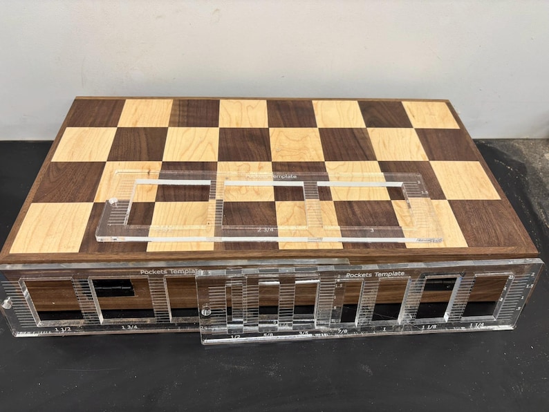 May include: A wooden chessboard with a checkerboard pattern of light and dark wood. A clear plastic template with the text "Pocket Template" is placed on top of the chessboard. The template has markings for pocket placement.