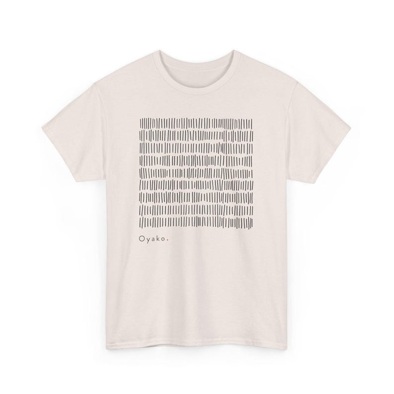 May include: Cream-colored t-shirt featuring a square pattern of vertical black lines. The word "Oyako" is printed in black below the pattern. The shirt has short sleeves and a crew neck.