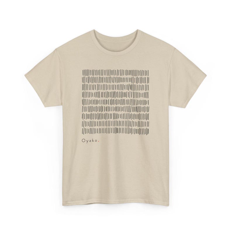 May include: A beige t-shirt featuring a black, rectangular pattern of vertical lines. The word "Oyako" is printed in black below the pattern. The shirt has short sleeves and a crew neck.