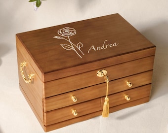 May include: A wooden jewellery box with a rose design and the name "Andrea" engraved on the lid. The box has four drawers and a gold tassel.