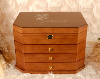 May include: A wooden jewelry box with a hexagonal shape and four drawers. The box is a warm brown color with gold-colored drawer pulls and a lock. The top of the box has an engraved floral design and the text "Our pretty little flower girl, Cecilia, Love Mama and Daddy."