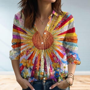 Può includere: Una camicia abbottonata a maniche lunghe con un vivace design a girasole. La camicia presenta un grande girasole strutturato al centro, con raggi colorati che si irradiano verso l'esterno. Il design incorpora vari motivi floreali e astratti in un mix di colori vivaci.