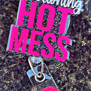 May include: A pink glitter badge with the text "High Functioning Hot Mess" and a clear plastic badge holder with a pink circle inside.