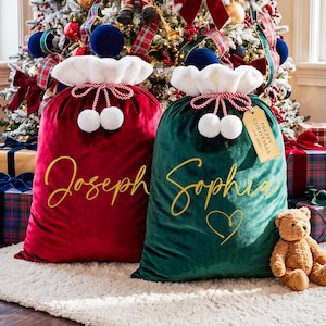 May include: Two velvet Christmas gift sacks, one deep red and one dark green, featuring white faux fur trim, red and white twisted rope drawstrings with white pom-poms, and gold script names. The green sack includes a tag reading PREPPY CHRISTMAS EST. 2025.
