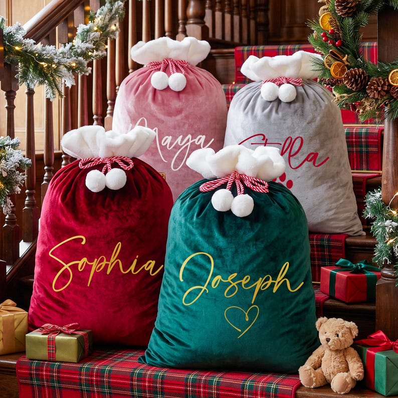 May include: Four velvet Santa sacks in red, green, pink, and gray, each featuring a white plush cuff, red and white drawstring with pom-poms, and personalized names in script font. The names Maya, Ella, Sophia, and Joseph are printed on the bags.