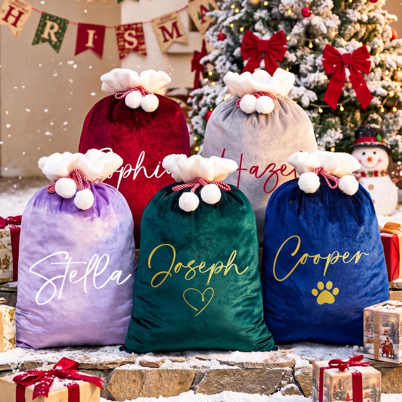 May include: Five plush velvet Christmas gift sacks in red, grey, lavender, dark green, and navy blue. Each sack features a white faux fur cuff with pom-poms, a drawstring closure, and personalized names in script font, including a paw print icon.