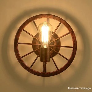 Wrought iron bicycle wheel lamp with light on, natural colour of wrought iron with warm yellow light in our opinion the idele colour to give the right light