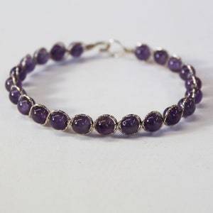 May include: A silver wire wrapped bracelet with purple amethyst beads.