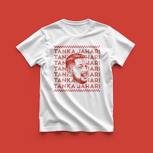 May include: White t-shirt with a red graphic of a man's face and the text "TANKA JAHARI" repeated vertically. The design is centered on the shirt, with a red background.