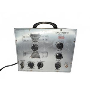 May include: A silver EICO Model 324 signal generator with a black top handle. The front panel features two arched frequency scales, six black control knobs, two audio input/output ports, and one RF output port. Text includes Signal Generator Model 324.