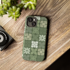 May include: A green phone case with a geometric pattern of white flowers and leaves. The case is designed for an iPhone.