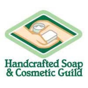 May include: A green diamond-shaped logo with the text "Handcrafted Soap & Cosmetic Guild" in white. The logo features a hand holding a small jar of cream and a bar of soap.