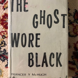 May include: A book cover with the title "The Ghost Wore Black" by Frances Y McHugh. The title is in bold, black font on a light grey background.