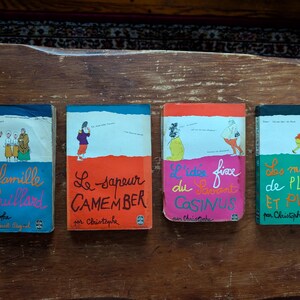 Puede incluir: Cuatro libros franceses antiguos con cubiertas coloridas. Cada libro presenta ilustraciones y títulos en francés, incluyendo "La famille Fenouillard", "Le sapeur CAMEMBER", "L'idée fixe du Savant COSINUS" y "Les malices de PLICK ET PLOCK".