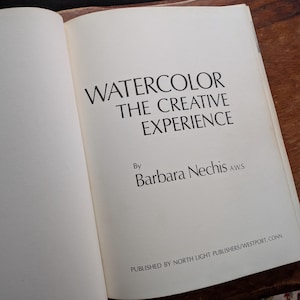 Puede incluir: Un libro abierto con el título "WATERCOLOR THE CREATIVE EXPERIENCE" de Barbara Nechis. Las páginas del libro son de color blanquecino y el texto está en una fuente oscura. Publicado por North Light Publishers, Westport, Conn.