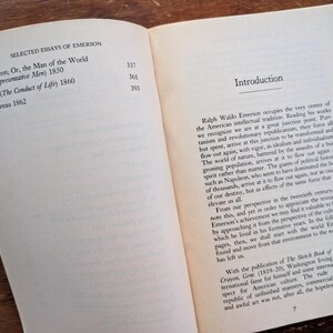K&ouml;nnte beinhalten: Ein ge&ouml;ffnetes Buch mit wei&szlig;em Hintergrund und braunem Einband. Das Buch tr&auml;gt den Titel "Selected Essays of Emerson" und enth&auml;lt eine Liste von Essays mit ihren Ver&ouml;ffentlichungsdaten. Der Text auf der rechten Seite ist eine Einleitung zum Buch, die sich mit den Werken von Ralph Waldo Emerson befasst.