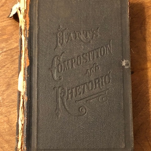 May include: A vintage, dark blue hardcover book titled "Harrys Composition and Rhetoric". The book is worn and has a torn spine.