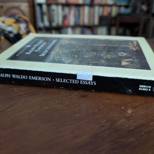 K&ouml;nnte beinhalten: Ein Taschenbuch mit schwarzem R&uuml;cken und wei&szlig;em Einband. Der Einband zeigt eine Waldszene in hellgr&uuml;nen und braunen Farbt&ouml;nen. Der Titel "Ralph Waldo Emerson - Selected Essays" ist in Schwarz auf dem R&uuml;cken gedruckt. Die ISBN-Nummer 0 14 03.9013 8 ist in der unteren rechten Ecke des R&uuml;ckens gedruckt.