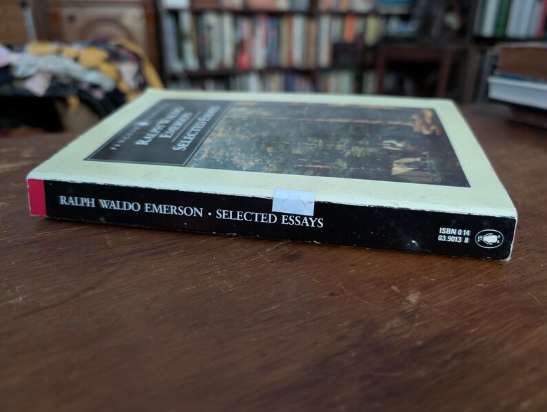 K&ouml;nnte beinhalten: Ein Taschenbuch mit schwarzem R&uuml;cken und wei&szlig;em Einband. Der Einband zeigt eine Waldszene in hellgr&uuml;nen und braunen Farbt&ouml;nen. Der Titel "Ralph Waldo Emerson - Selected Essays" ist in Schwarz auf dem R&uuml;cken gedruckt. Die ISBN-Nummer 0 14 03.9013 8 ist in der unteren rechten Ecke des R&uuml;ckens gedruckt.