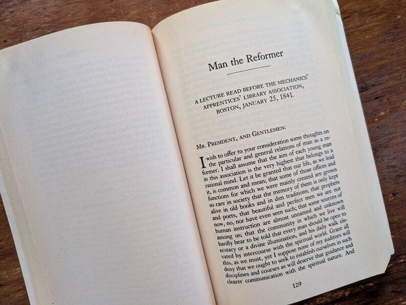 K&ouml;nnte beinhalten: Eine Seite aus einem Buch mit dem Titel "Der Mensch, der Reformer" mit dem Text "Ein Vortrag, gehalten vor der Mechanics' Apprentices' Library Association, Boston, am 25. Januar 1841." Der Text auf der Seite behandelt die Rolle eines Reformers in der Gesellschaft.