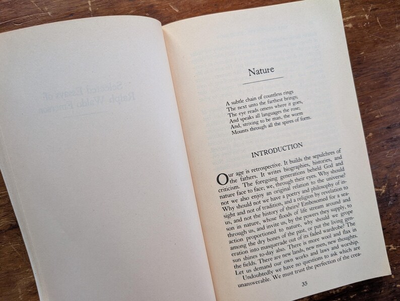 K&ouml;nnte beinhalten: Ein offenes Buch mit wei&szlig;em Hintergrund und schwarzem Text. Das Buch tr&auml;gt den Titel "Natur" und der Text behandelt die Natur unseres Zeitalters und unsere Beziehung zum Universum. Der Text enth&auml;lt den Satz "Unser Zeitalter ist retrospektiv."
