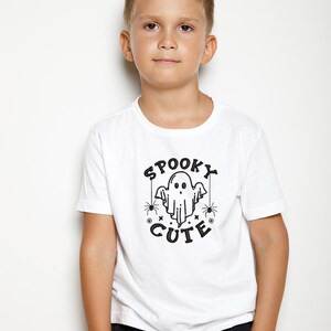 May include: A white t-shirt with a black graphic of a ghost with the text "Spooky Cute" and spiders.
