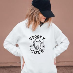 May include: White hoodie with a black graphic of a ghost with the text "Spooky Cute" on it.
