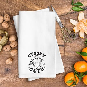 May include: White kitchen towel with a black embroidered design of a ghost with the text "Spooky Cute".