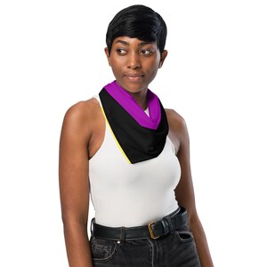 May include: A non-binary pride flag bandana featuring a purple stripe, a black stripe, a yellow stripe, and a white background. The bandana is worn around the neck.