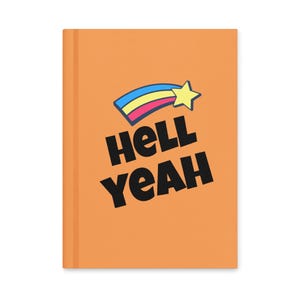 May include: Orange notebook with the words "HELL YEAH" in bold black letters. Above the text is a shooting star design with blue, yellow, and pink colors. The notebook has a clean, minimalist design.
